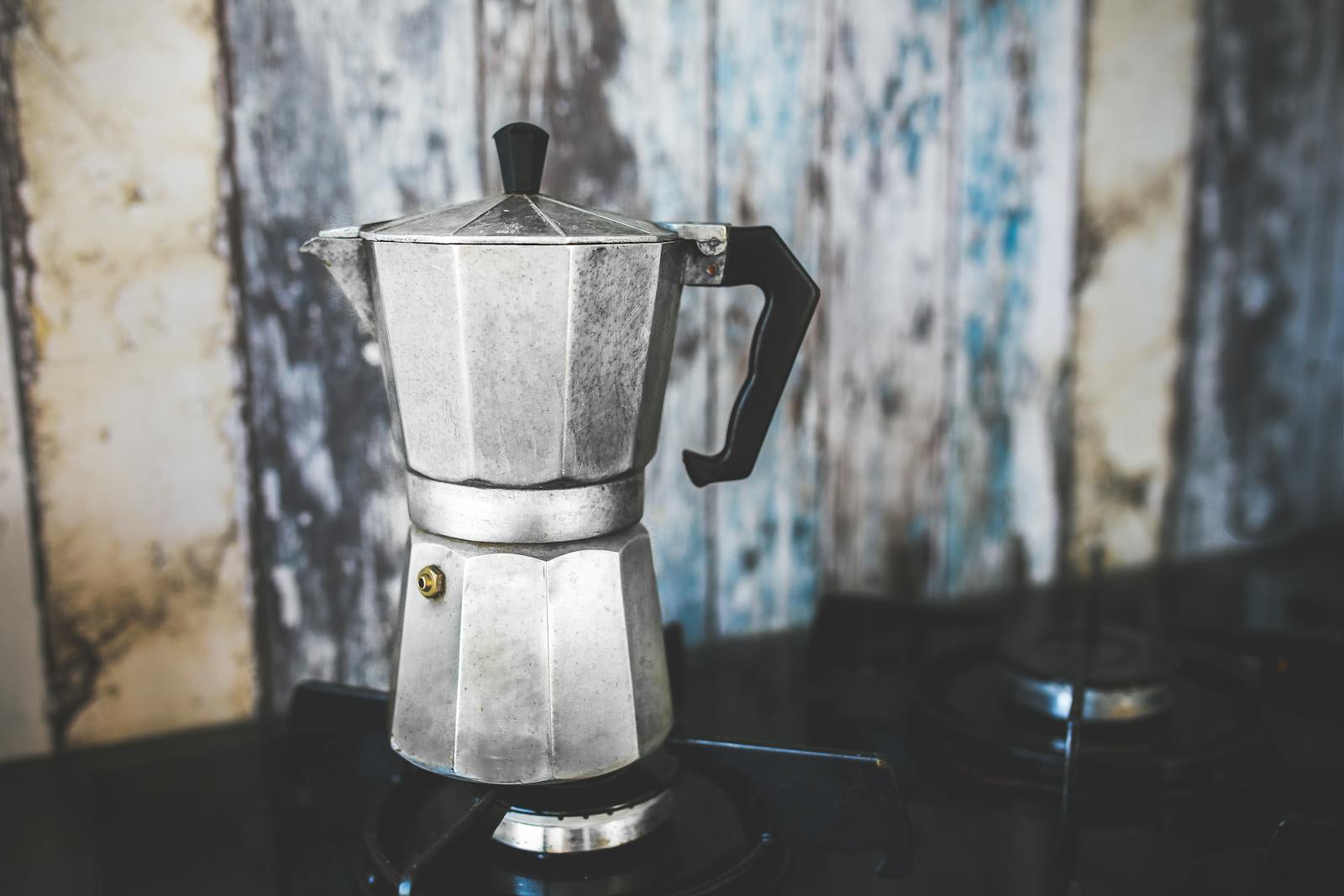 A vintage Italian moka pot on a stovetop, brewing fresh espresso.